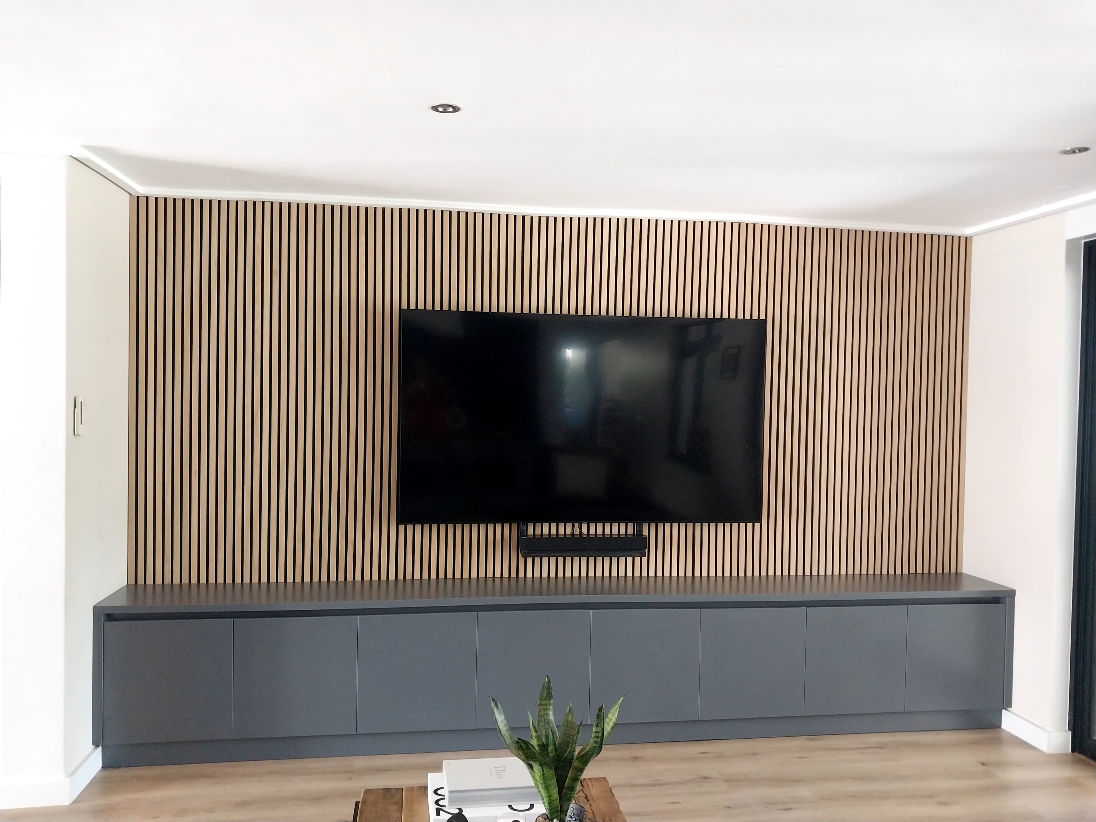 TV feature wall with wood slat panelling and charcoal floating unit